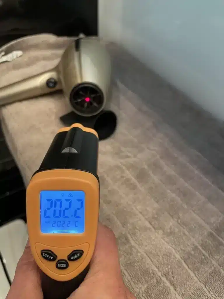 Harfon-mata-temperatur Testlabbet mäter temperaturen vid utblåset på en hårfön med IR-mätare